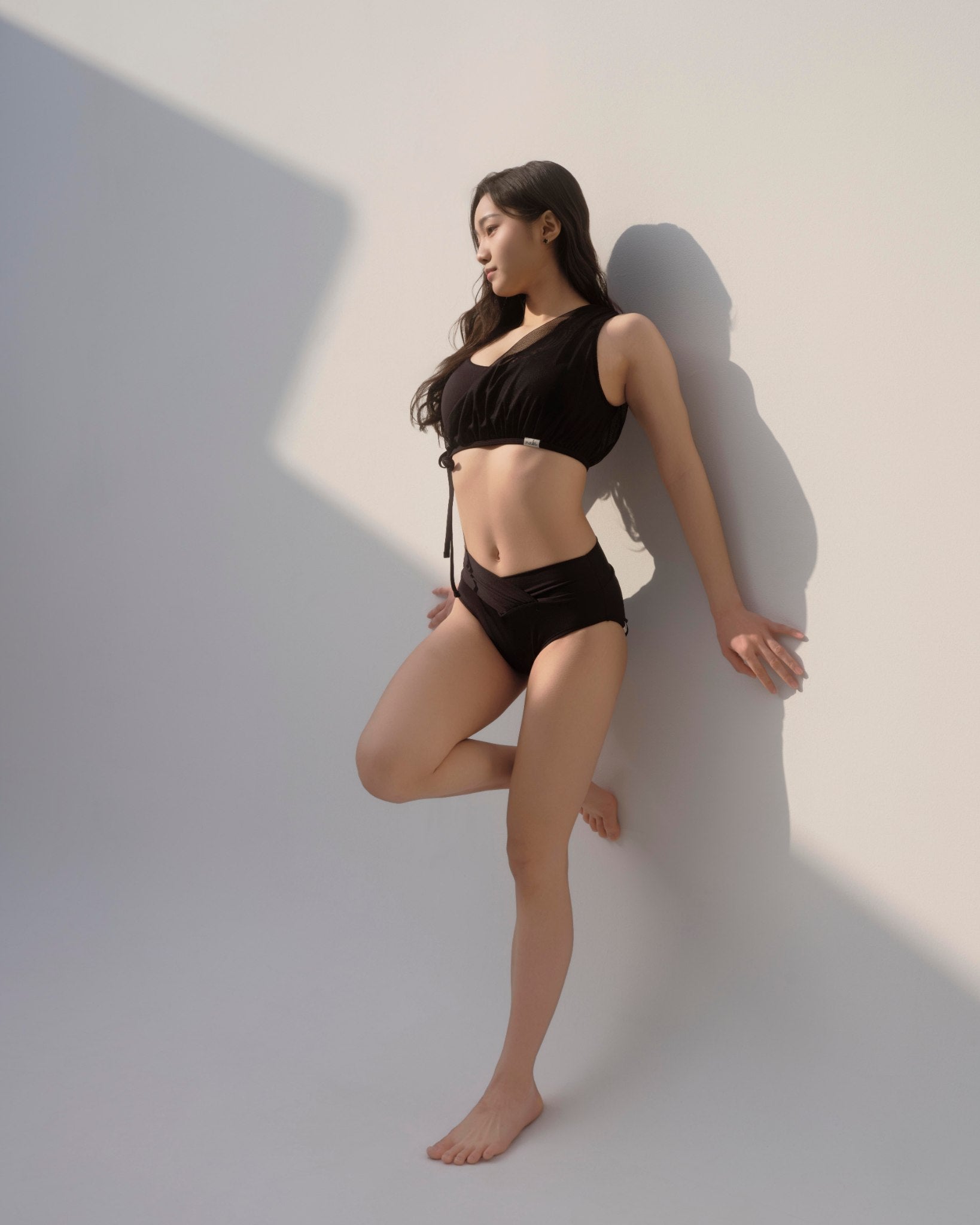Woman modeling the Metamorphosis Signature Set - Black, available in sizes S, M, L. Sustainable polewear featuring a mesh overlay, adjustable straps, and V-cut bottom.