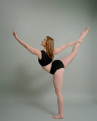 Woman performing a dance pose in the Metamorphosis Signature Set - Black, available in sizes S, M, L. Sustainable polewear designed for flexibility and elegance.

