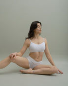 Woman stretching in Metamorphosis Signature Set - White, available in sizes S, M, L. Sustainable polewear designed for flexibility, elegance, and comfort.

